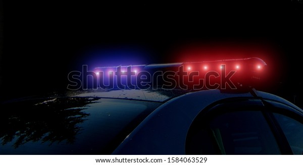 Blurred defocused silhouette of road police\
patrol car on the street of city at night. Flashing red and blue\
police car led lights in night time. The roof-mounted lightbar\
alarm emergency\
lighting