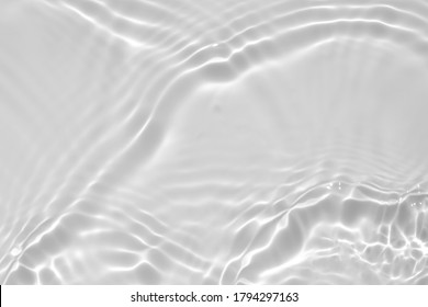 Blurred desaturated transparent clear calm water surface texture with splashes and bubbles. Trendy abstract nature background. White-grey water waves in sunlight.