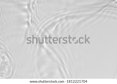 Blurred desaturated transparent clear calm water surface texture with splashes and bubbles. Trendy abstract nature background. White-grey water waves in sunlight. Copy space.