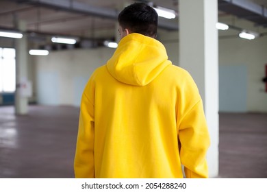 Blurred Details Of Oversized Hoodie  At Model Indoors.Back View At A Man  In Oversize Hoodie.fashion And Wear Concept.warm Oversized Wear.space For Text And Logo.back View Of Yellow  Hoodie.