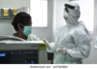 Blurred Doctor In Protective Clothing Taking Patient Suspected Of Being Infected By Virus Outbreak (Coronavirus COVID-19, Ebola, SARS)  In Quarantine Room At Hospital