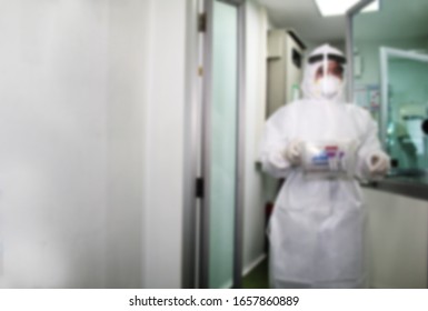 Blurred Doctor In Protective Gown Taking Tube Blood Of Patient To Test For Outbreak Of Infected Virus (Coronavirus COVID-19, Ebola, SARS) In Science Laboratory At Hospital.