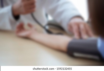 Blurred. Doctor Testing Blood Pressure With Sick Patient In Hospital. Doctor Diagnose Patient's Sickness & Consider Medication For Ill Patient. Physician And Patient & Hyper Tension Testing Concept.