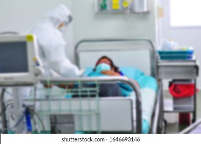 Blurred Doctor Is Treating Patient Infected By Virus Outbreak (Coronavirus COVID-19, Ebola, SARS) In The Quarantine Room At Hospital.