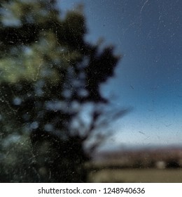 Blurred Dusty Car Window Close Up With A Blurred  Tree Landscape Background