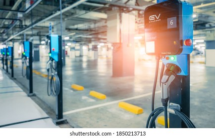 Blurred electric car charging station for charge EV battery. Plug for vehicle with electric engine. EV charger. Clean energy. Charging point at car parking lot. Future transport technology.