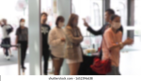 Blurred of The employee brought the device to check the customer fever  At the mall entrance  Be careful of people with high body temperatures or fever. Prevent coronavirus infection.surgical mask. - Powered by Shutterstock