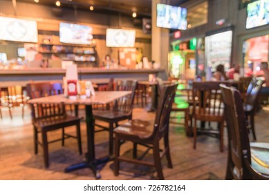 Blurred Empty Sport Bar/pub With Row Of Hanging TVs Big Screens At Famous Bourbon Street In New Orleans, Louisiana, USA. Classic Wooden Table, Chair. Happy Hour And Night Club Concept.