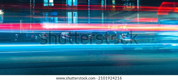 blurred fast moving transport. night city road\
traffic. long exposure tracer cars lights. blue and red color lines\
from vehicles headlights. abstract vibrant color dark time city\
life picture.