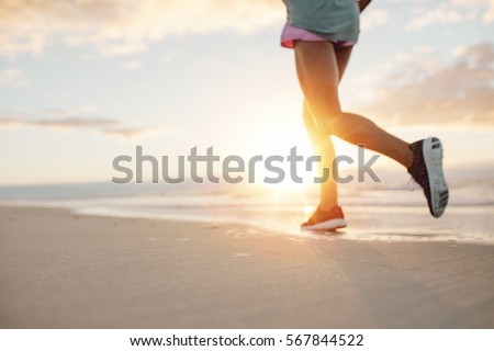 Blurred Feet of young woman jogging on the beach. Fitness female on morning run at sea shore.