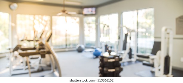 Blurred Fitness Center With Cardio Machines And Weight, Strength Training Equipment. Empty Gym Facility Service Room In Apartment Building Complex At Houston, Texas, US. Panorama Banner Presentation.