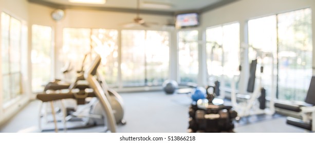 Blurred Fitness Center With Cardio Machines And Weight, Strength Training Equipment. Empty Gym Facility Service Room In Apartment Building Complex At Houston, Texas, US. Panorama Banner Presentation.