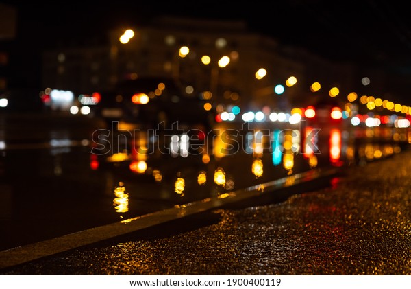 Blurred focus\
of a central city road during the rain at night, with colorful\
unfocused lights in the background. Water from the rain and the\
reflection of lanterns in the\
city.