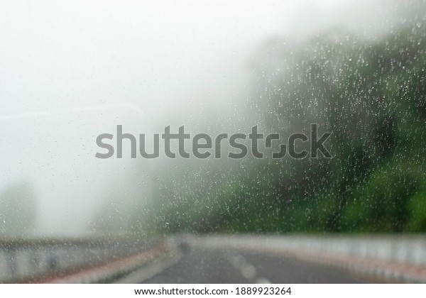 Blurred Foggy and Drizzle on the\
windshield of the car when driving on the road, Blurred\
background