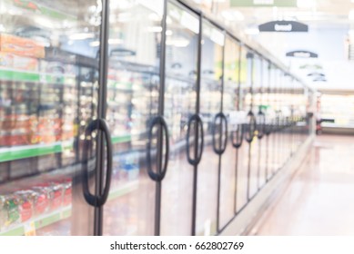 Blurred Frozen Food Section At Retail Store In America. Huge Glass Door Aisle With Variety Pack Of Processed Fruit, Vegetable, Breakfast, Appetizer, Side, Meals, Pizza. Food In Supermarket Background