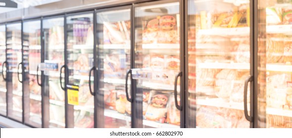 Blurred Frozen Food Section At Retail Store In America. Huge Glass Door Aisle With Variety Pack Of Processed Pizza. Freezer Full Assortment Of Frozen Pizza In Local Supermarket, Defocused Background.