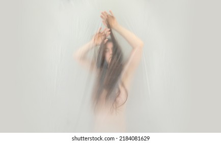 Blurred, Fuzzy Image Of Sensual Dreamy Portrait Of A Young Woman Surrounded By Long Brunette Hair Floats Up In Sensual Erotic Dream World Behind Plastic Foil, Copy Space