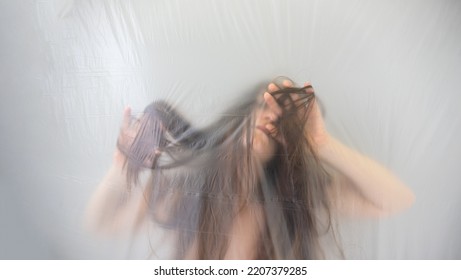 Blurred, Fuzzy Image Of Sensual Romantic, Young Woman Moving In Trance, Playing With Her Long Hair, Behind Transparent Plastic Foil Film, Copy Space