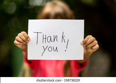 Blurred girl holding a piece of paper with the words Thank You in front of her. - Shutterstock ID 198738329