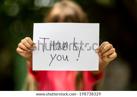 Blurred girl holding a piece of paper with the words Thank You in front of her.