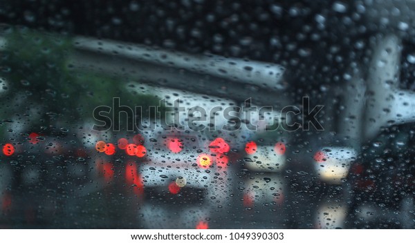 Blurred, Grain image. Selective focus. Car windshield\
view. Raindrop on the windshield with traffic in the city on a\
rainy day. 