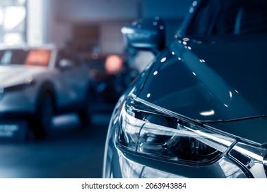 Blurred grey car parked in luxury showroom. Closeup new car parked in modern showroom.  Automobile leasing and insurance background. Automotive industry. Auto leasing business. Eelctric vehicle.