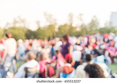 Blurred group of mixed race, ethnic, diverse culture audience sitting on grass, chair, tent on a hillside and enjoy outdoor music festival, open-air concert held in public park at downtown Houston, TX