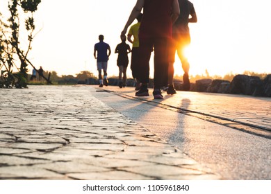 Blurred Group Of Runner Are Running In Park At Evening Sunset. People Walking And Exercise. Fitness And Healthy Activity Lifestyle.