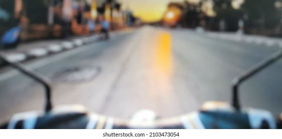 Blurred handlebar of motocycle on the empty country road with the sunset light at end of way.