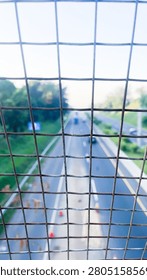 Blurred Highway View Through Wire Fence with Green Landscape and Urban Transportation Concept