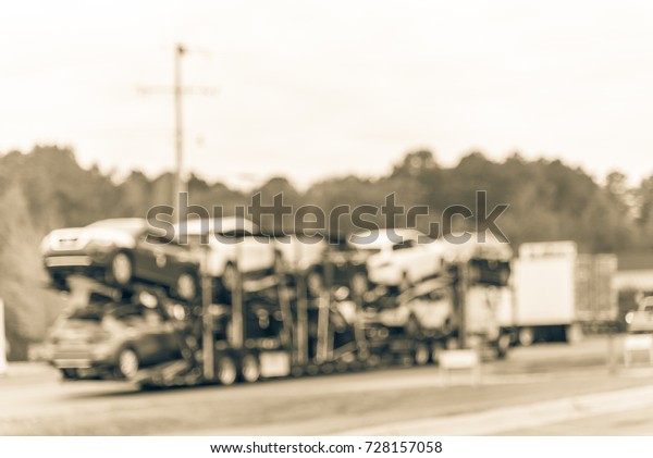 Blurred huge car carrier truck of new cars for batch\
delivery to dealership. Full load transport truck of new vehicles\
in transit  in Texas, USA. Automotive industry abstract background.\
Vintage tone