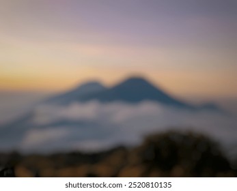 Blurred Image Background of Aerial peak view over green pass into deep rocky gorge with sharp cliffs silhouetted against huge mountain under clouds in blue sky. Dramatic layered views.Photo Beautiful  - Powered by Shutterstock