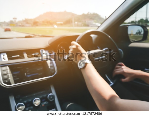 Blurred image background of elder man\
driving a car with his hands on the steering\
wheel