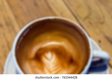 Blurred image for background of empty coffee cup on wooden table, still latte art in the bottom of the cup.