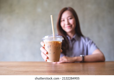 Blurred Image Of A Beautiful Young Asian Woman Holding And Serving A Glass Of Iced Coffee