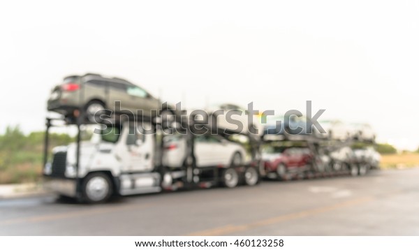 Blurred image a big car carrier truck of new cars
for batch delivery to dealership. Full load transport truck of new
vehicles on country road. Automotive industry abstract background.
Panorama style.