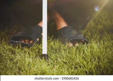 Blurred Image Blind Senior, Visually Impaired, Homeless, Using A White Cane Sitting On The Grass: Concept White Cane Safety Day