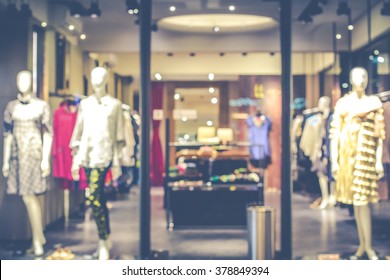 Blurred Image Of Boutique Display Window With Mannequins In Fashionable Dresses For Background. Toned Image.