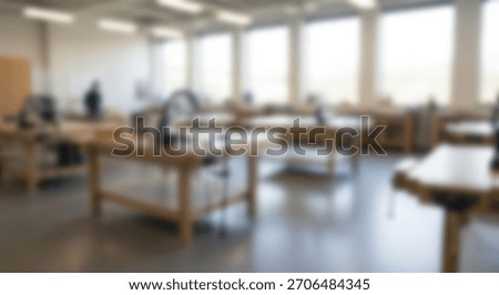 A blurred image of a bright carpentry workshop with woodworking benches, perfect for background use.