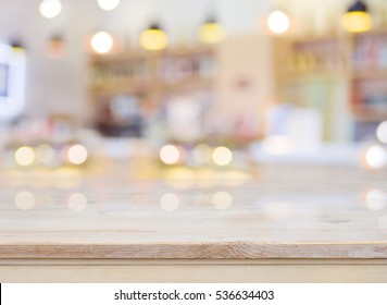Blurred image of cafe interior with wooden table in front.