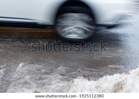 Blurred image of a car driving on a wet asphalt road in winter. Close-up.