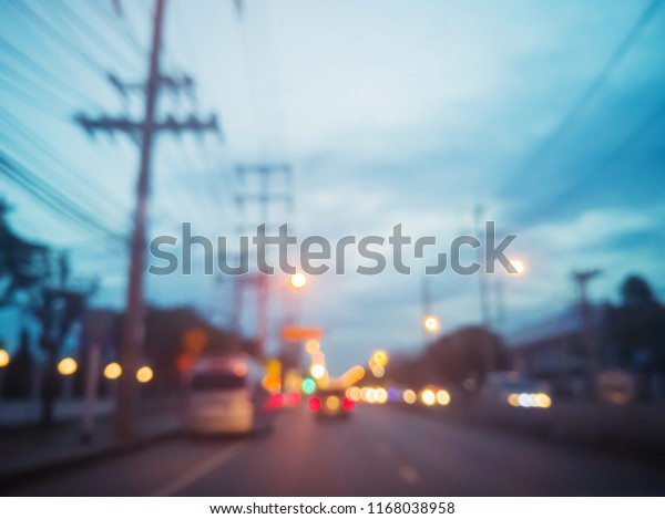 Blurred image of cars on the road with\
lanterns traffic lighting, car lighting and blue sky in evening\
time abstract bokeh\
background