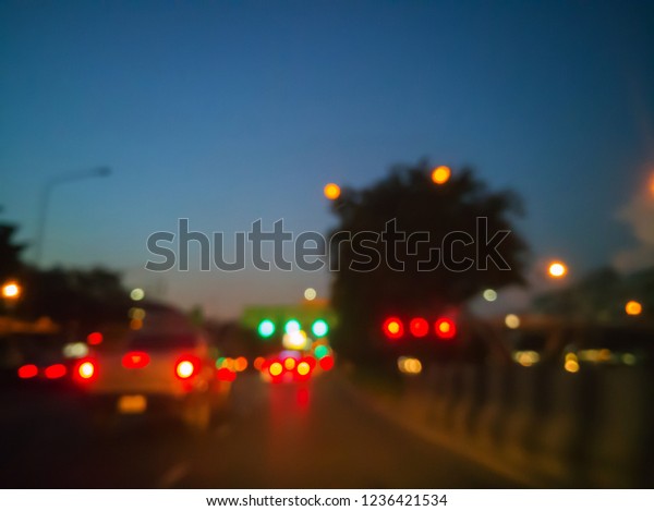 Blurred image of cars on the road with\
lanterns traffic lighting, car lighting and blue sky in evening\
time abstract bokeh\
background