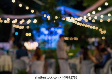 Blurred image of celebrate outdoor wedding party in the garden night time for background usage.