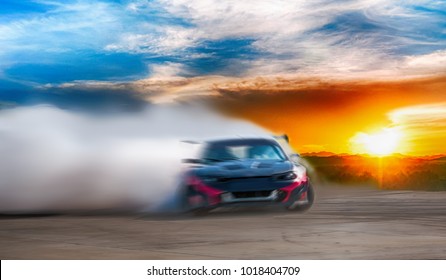 Blurred Of Image Diffusion Race Drift Car With Lots Of Smoke From Burning Tires On Speed Track At Sunset.