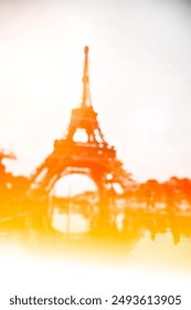 A blurred image of the Eiffel Tower in Paris with a warm yellow and orange gradient.