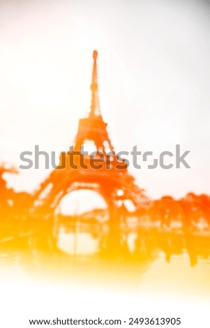 A blurred image of the Eiffel Tower in Paris with a warm yellow and orange gradient.