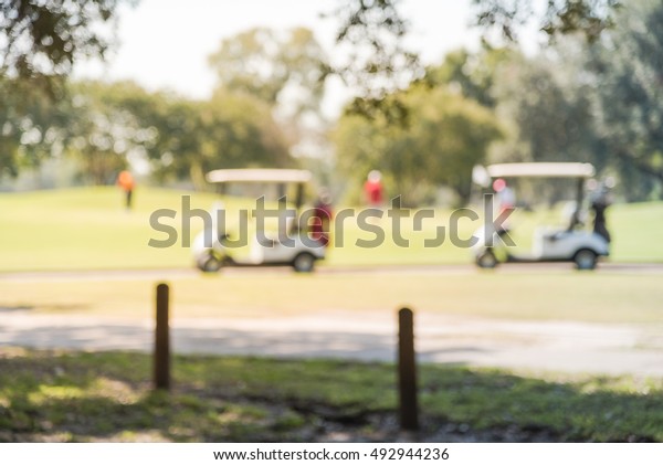 Blurred image of electric\
golf carts in a sunny day at the golf course in Houston, Texas, US.\
Caddy on the golf course abstract background. Outdoor sport vehicle\
concept.