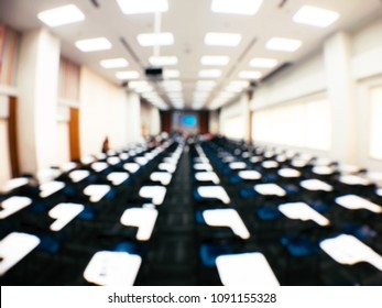 Blurred Image Of Empty Large Examination Room With Wooden Chairs Style. No People