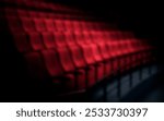 Blurred image of empty red theater seats in a dimly lit auditorium. Red seats, theater, and auditorium create a dramatic, mysterious atmosphere. Red cinema theater seats.